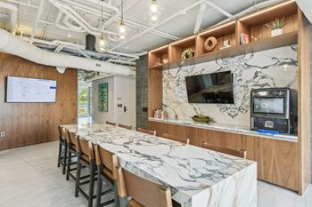 A long marble table with chairs in a room with a tv
